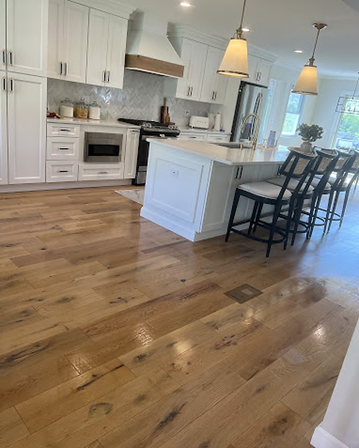 Bright modern kitchen with island, gleaming hardwood floors, and white cabinetry